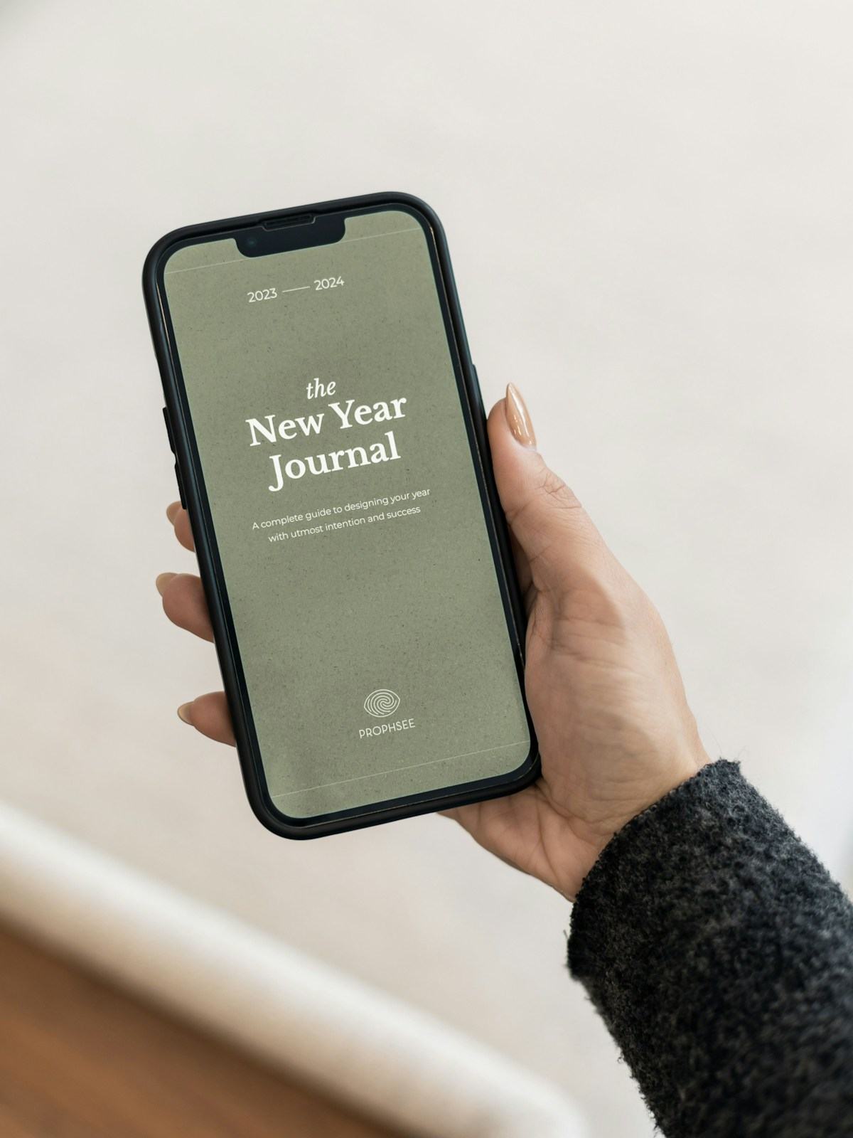 A hand holding a smartphone displaying a journal app screen