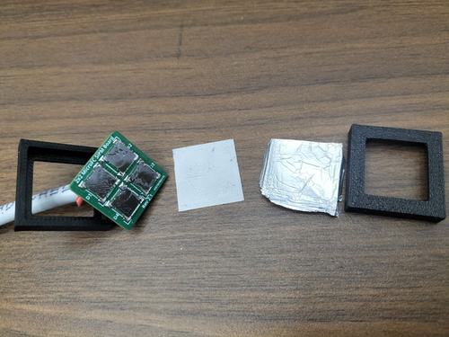 Alpha detector parts laid out in a row: 3D-printed frame, 2×2 SiPM board, ZnS(Ag) scintillator film, aluminium foil, frame